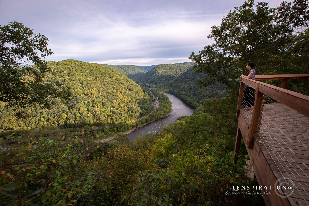 Someone standing on an observation deck overlooking a mountain and river scene in West Virginia
