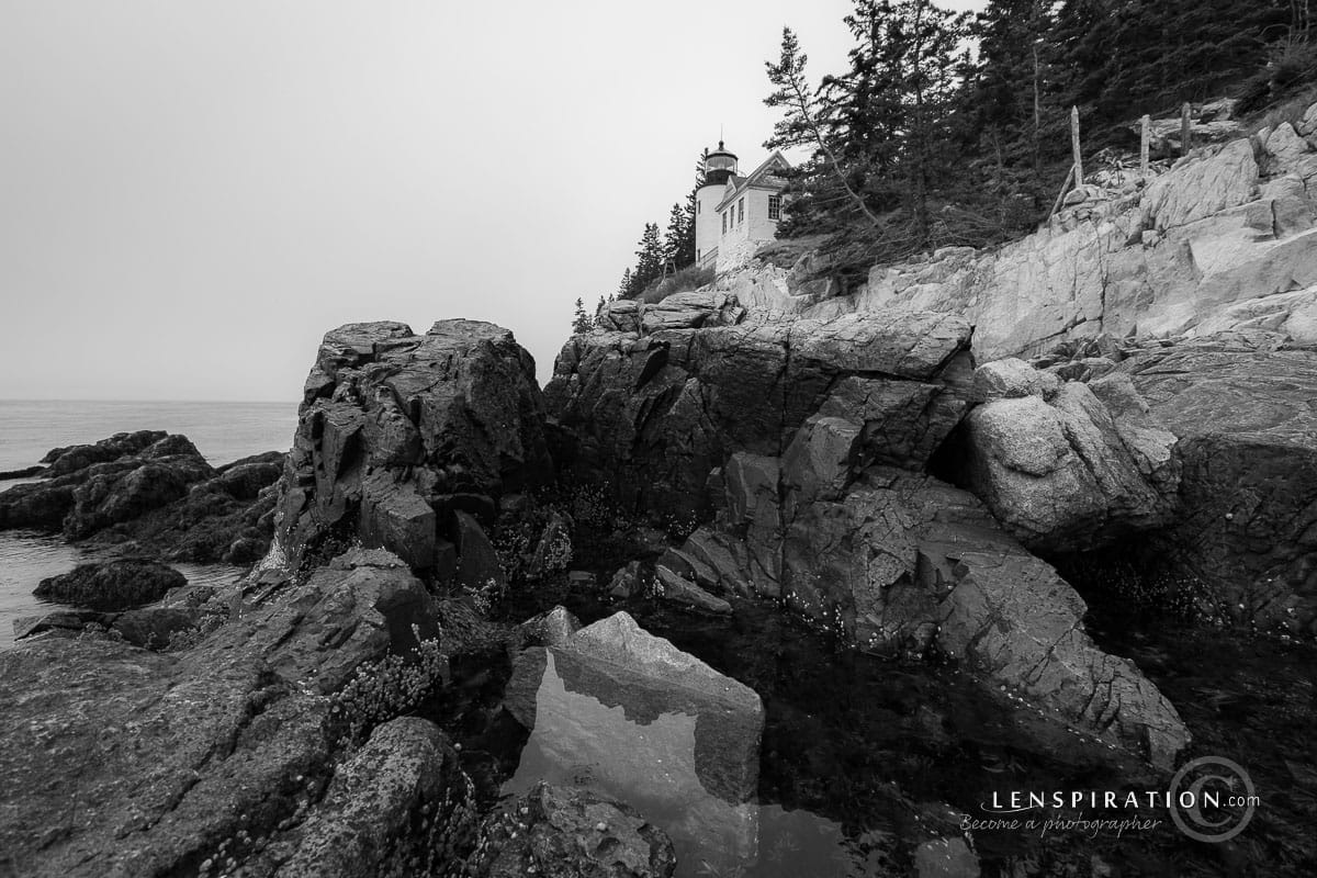 Bar Harbor Light at Acadia National Park with rocky foreground on cloudy day