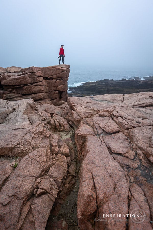 Photographer stands on rock outcropping at Acadia National Park, Maine, UA